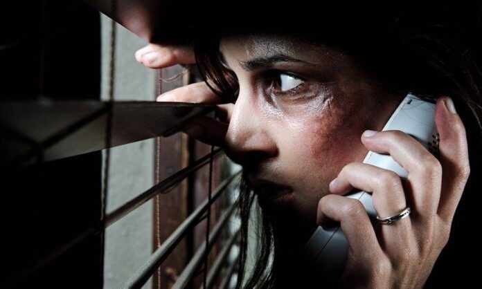 Fearful battered woman peeking through the blinds to see if her